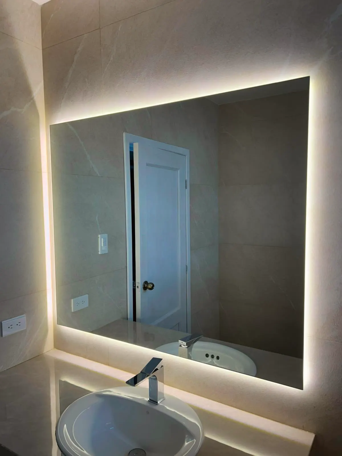 Espejo retroiluminado rectangular sobre el lavabo, con la luz perimetral encendida