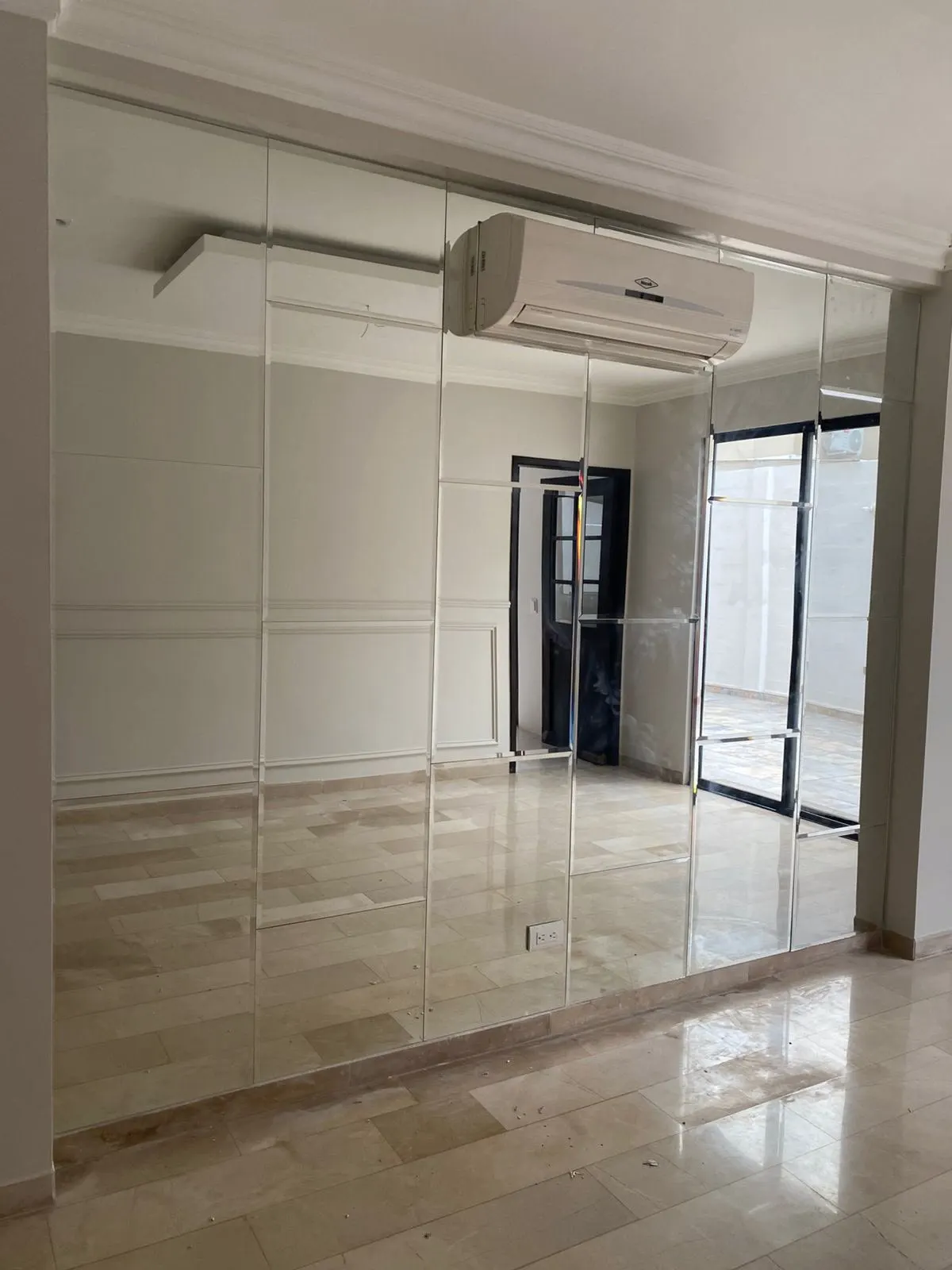 Pared espejada de piso a techo en la sala, sobre piso de mármol