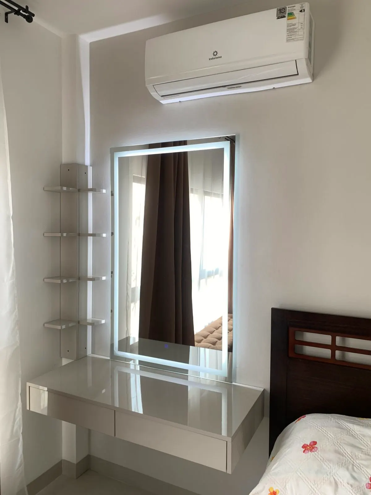Espejo retroiluminado sobre el tocador de un dormitorio, reflejando la cama