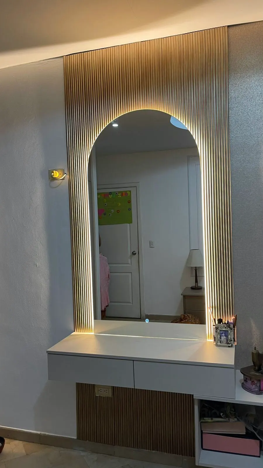 Espejo de arco retroiluminado sobre un tocador con frente de listones